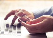 Mãos de um homem segurando um cadeado enquanto digita no teclado de um notebook