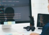 Programador olhando para um monitor com várias linguagens de programação