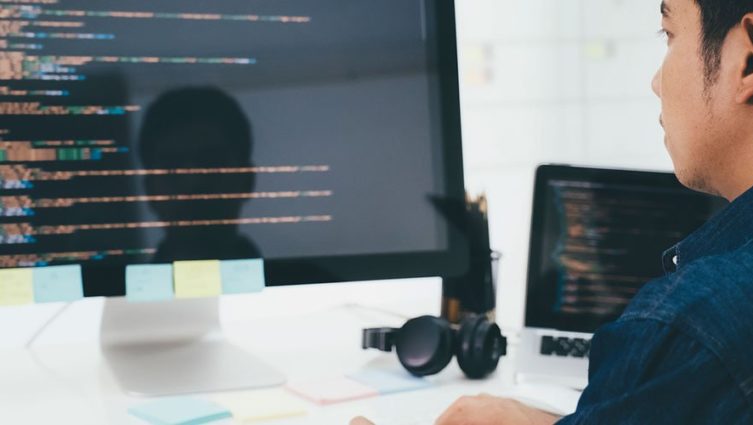 Programador olhando para um monitor com várias linguagens de programação