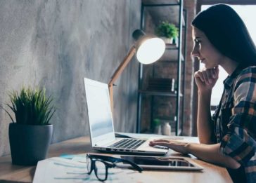 Mulher sentada em um escritório olha para a tela de seu computador enquanto trabalha