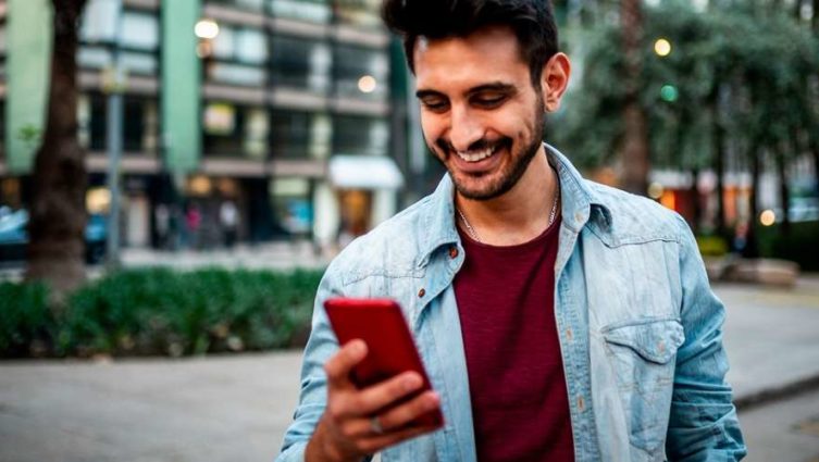Homem olha para um telefone celular em uma interação de consumo