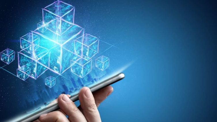 Mão segurando um smartphone com blocos de blockchain saltando da tela do aparelho