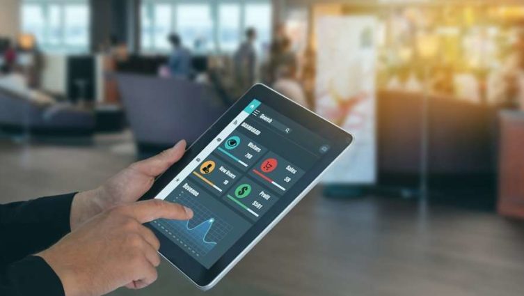 Imagem conceito do uso de machine learning e inteligência artificial em uma loja. Pessoa segura um tablet, que contém dados que podem ajudar na tomada de decisão