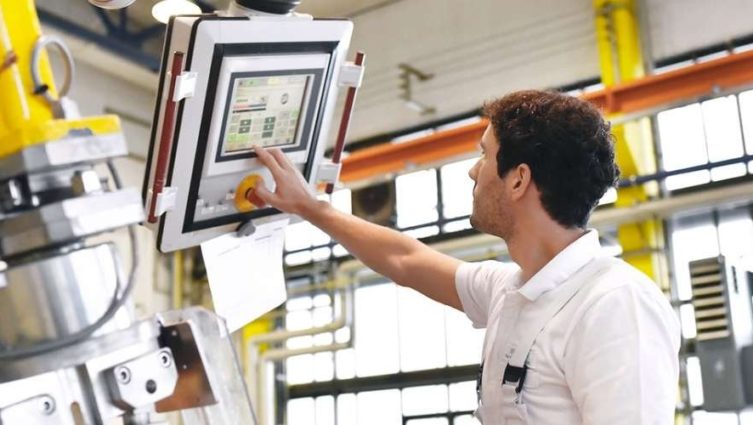 Imagem de um engenheiro mecânico operando uma máquina em uma indústria